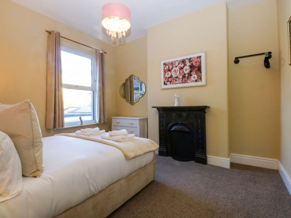 A bedroom with a bed, mirror, and fireplace at Curzon Heights in Llandudno