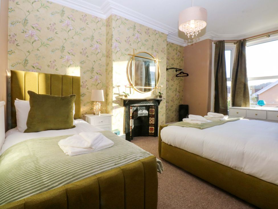 A bedroom with two beds and a fireplace at Curzon Heights in Llandudno