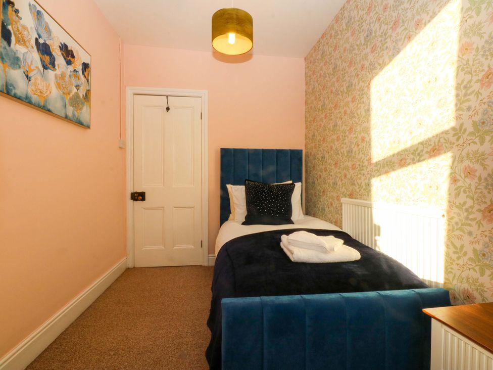 A bedroom with a single bed and a door at Curzon Heights in Llandudno