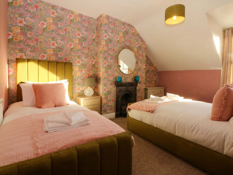 A bedroom with two beds and floral wallpaper at Curzon Heights in Llandudno