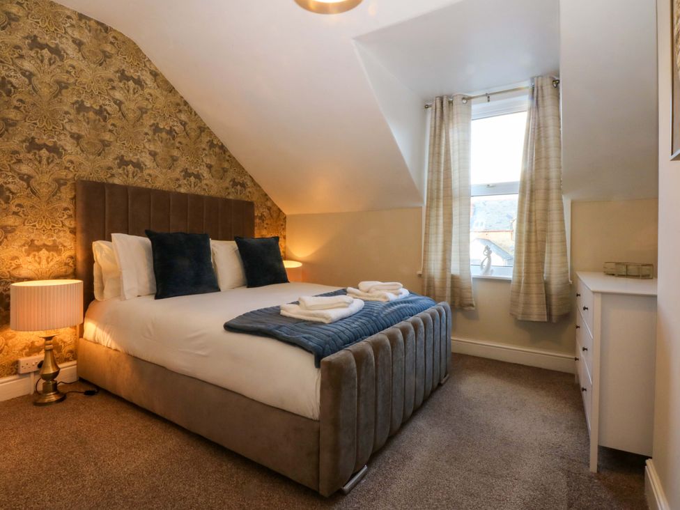 A bedroom with a bed and dresser at Curzon Heights in Llandudno