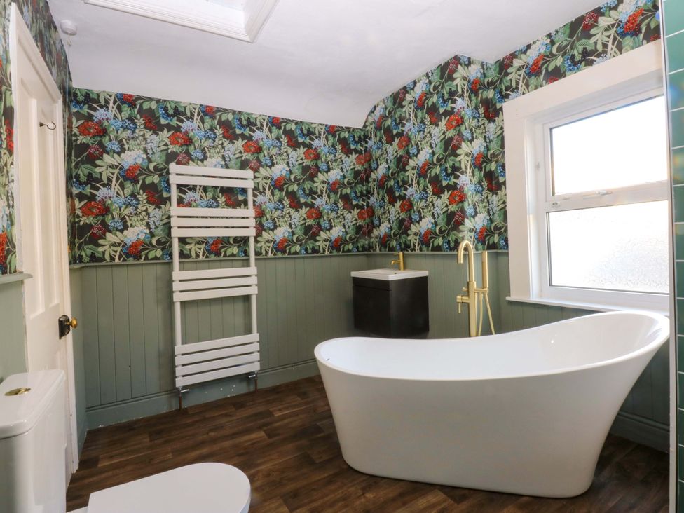 A bathroom featuring a bathtub, toilet, radiator, and sink at Curzon Heights in Llandudno