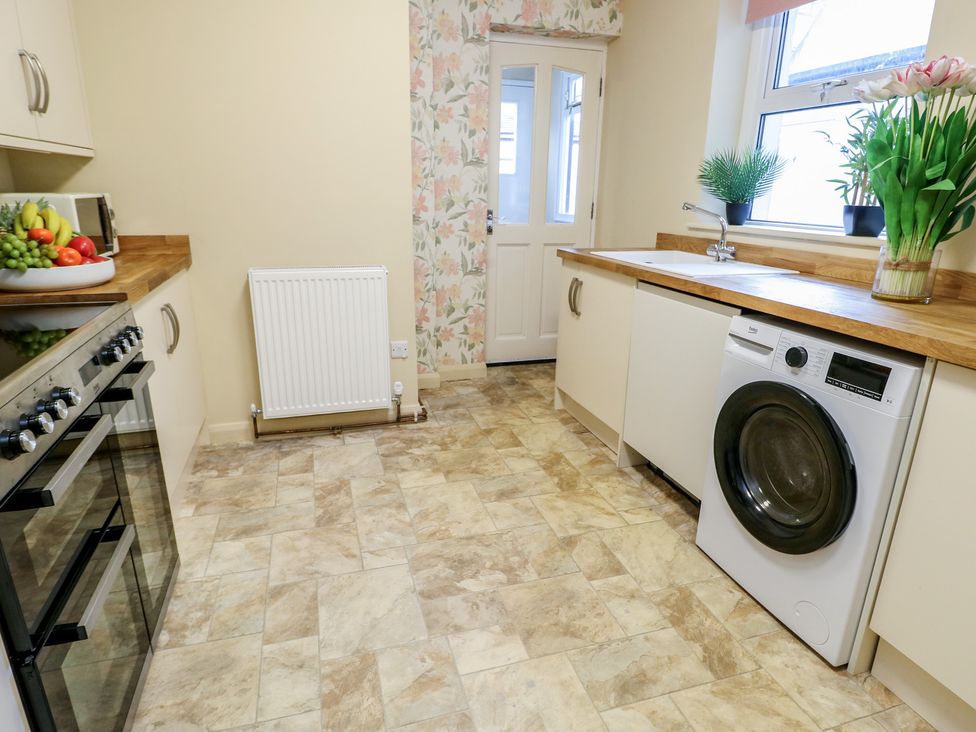 A kitchen with a washing machine and fruit bowl at Curzon Heights in Llandudno
