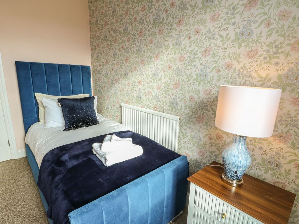 A bedroom with a single bed and bedside lamp at Curzon Heights in Llandudno