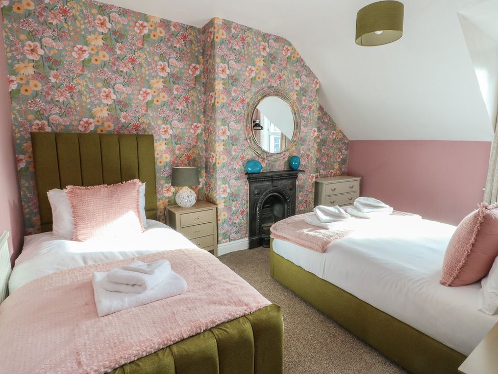 A bedroom with two beds and a mirror at Curzon Heights in Llandudno