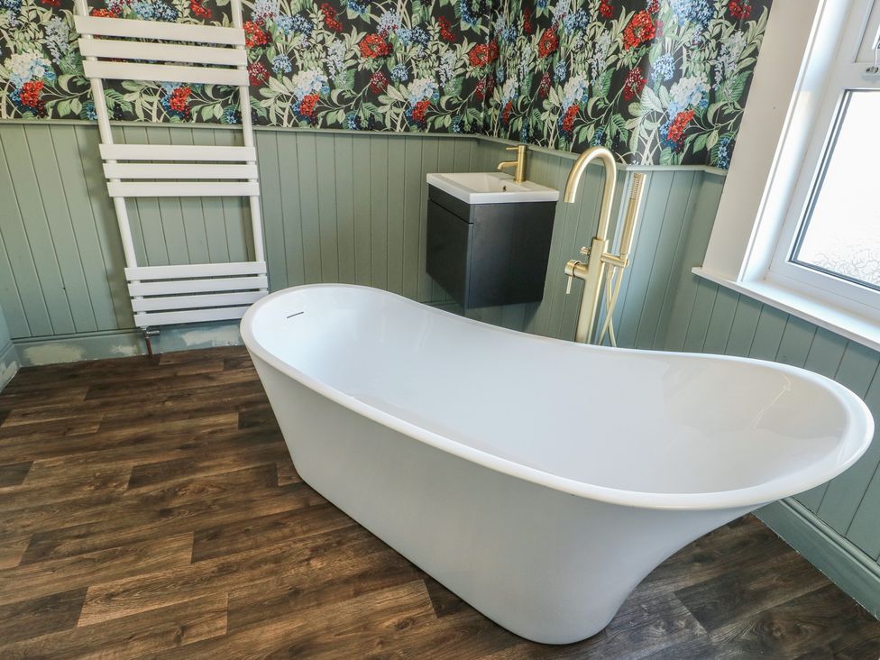 A bathroom featuring a bathtub and sink at Curzon Heights in Llandudno