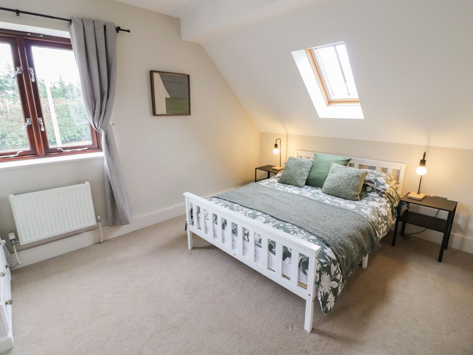 A bedroom with a bed and windows at Little Acre in Church Lench near Harvington