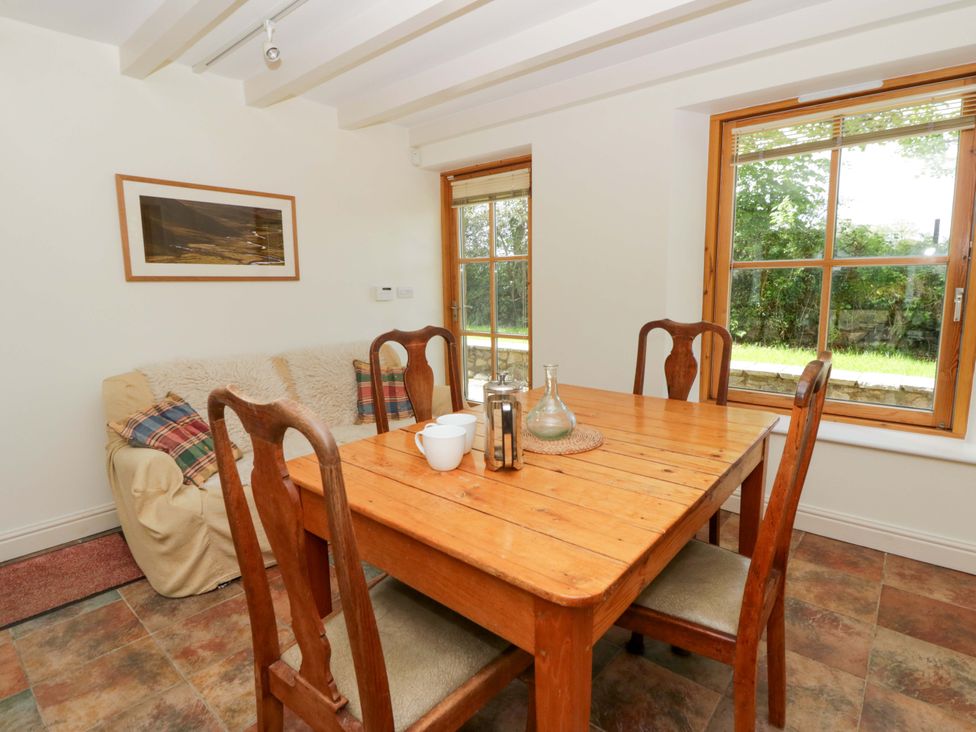 A dining room with a wooden table and chairs at Bryn Isaf in Swyddffynnon near Pontrhydfendigaid
