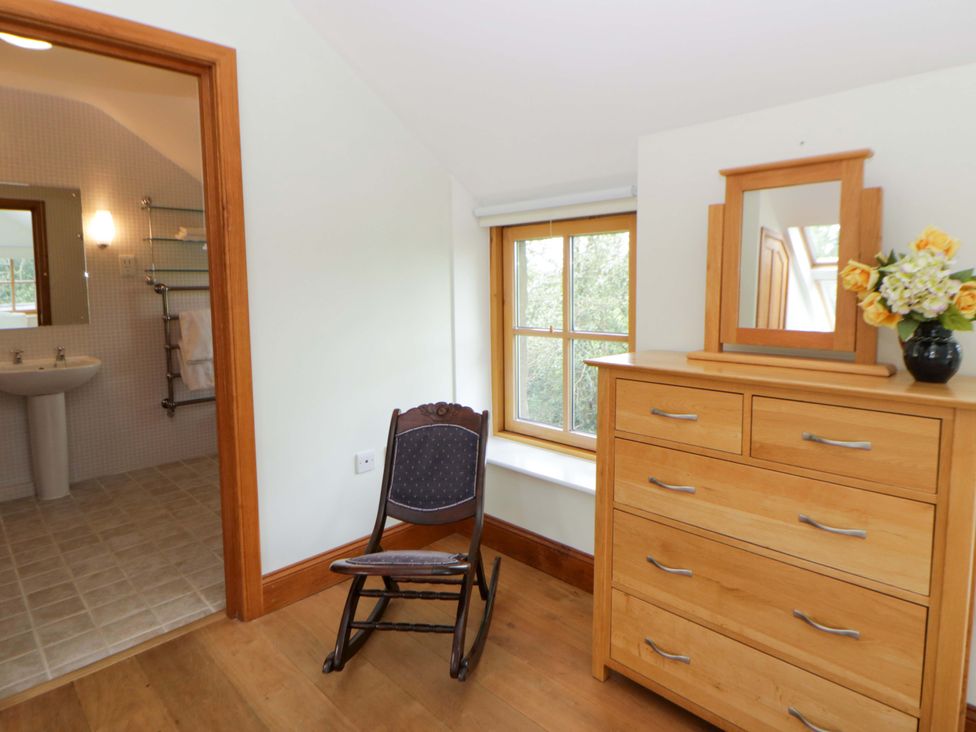 A bedroom with a rocking chair and dresser at Bryn Isaf in Swyddffynnon near Pontrhydfendigaid