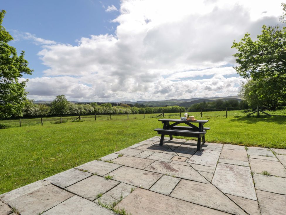 A picnic table on a slate patio with grass in Bryn Isaf near Swyddffynnon near Pontrhydfendigaid