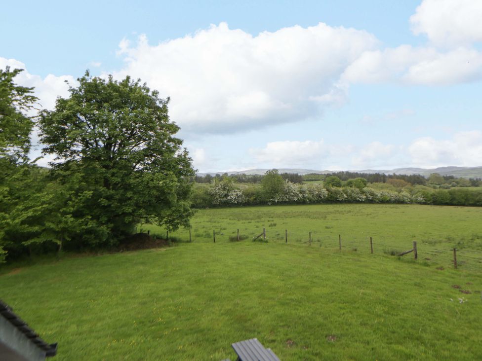 View of a grassy field with trees and clouds at Bryn Isaf in Swyddffynnon near Pontrhydfendigaid