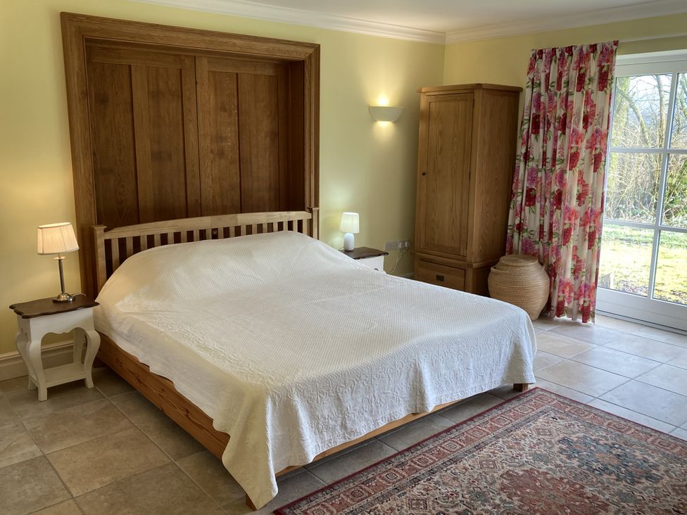 A bedroom with a bed, nightstand, and wardrobe at Ty Cellin in Ystrad Meurig