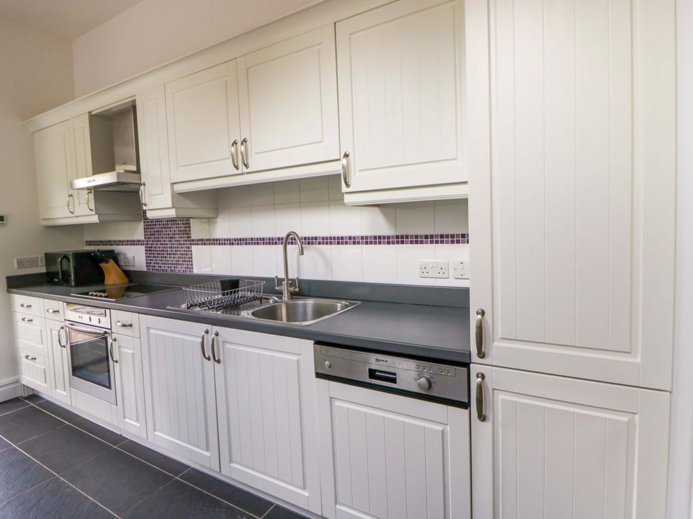 A kitchen with a sink, cooker, and microwave at Ty Cellin in Swyddffynnon near Pontrhydfendigaid