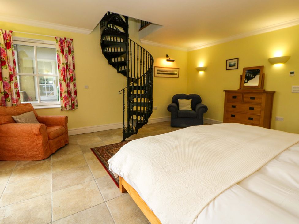 A bedroom with a bed, staircase, and furniture at Ty Cellin in Swyddffynnon near Pontrhydfendigaid