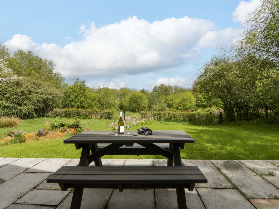 A table with a bottle and glasses in a garden at Ty Cellin in Swyddffynnon near Pontrhydfendigaid