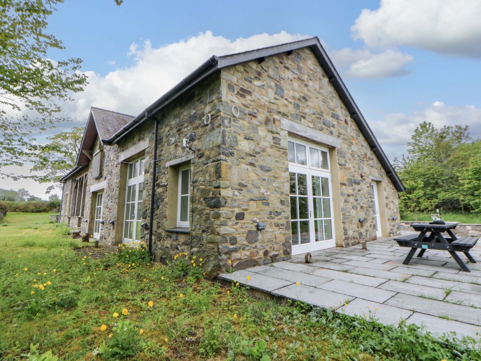 An outdoor area with a stone wall and table at Ty Cellin in Swyddffynnon near Pontrhydfendigaid