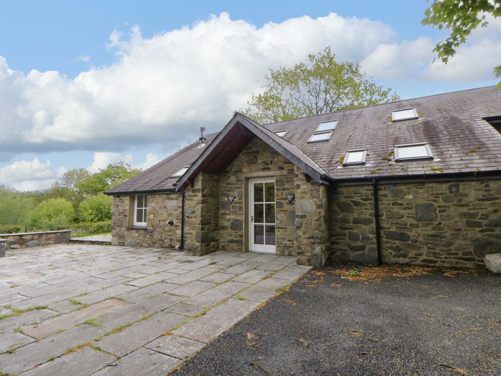 An exterior view of a stone house with a slate patio at Ty Cellin in Sywyddffynnon near Pontrhydfendigaid