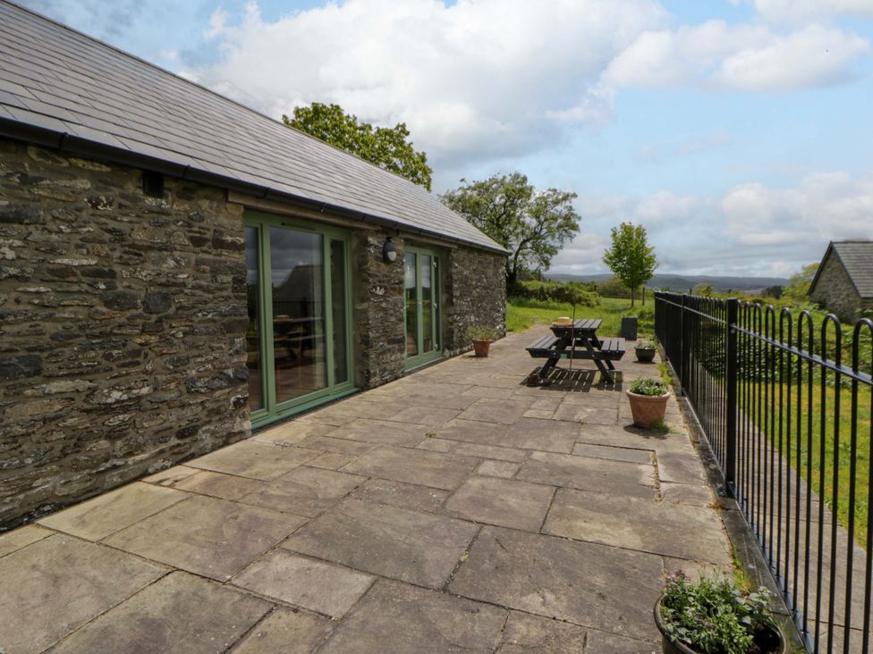 An outdoor area with a stone wall, patio seating and planters at Cwtch in Swyddffynnon near Pontrhydfendigaid