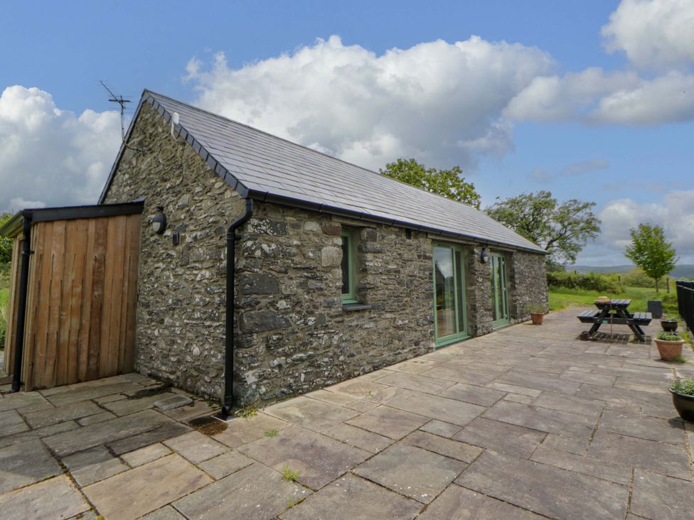 A stone house with a patio and dining table at Cwtch in Swyddffynnon near Pontrhydfendigaid