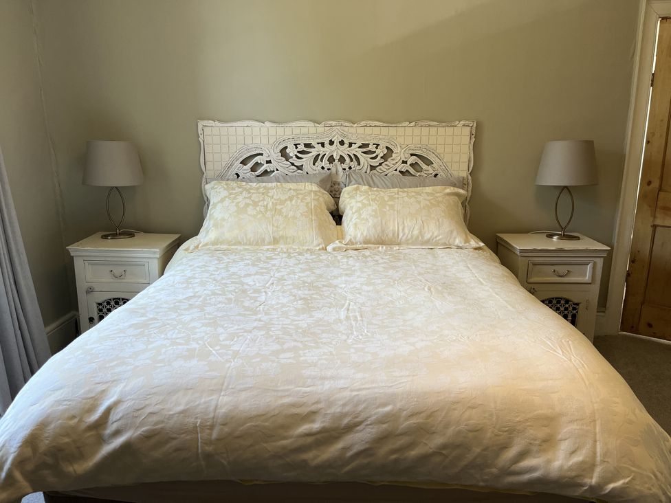 A bedroom with a double bed with an ornate headboard two bedside tables each with a lamp at Humphreston House in Temple Cloud