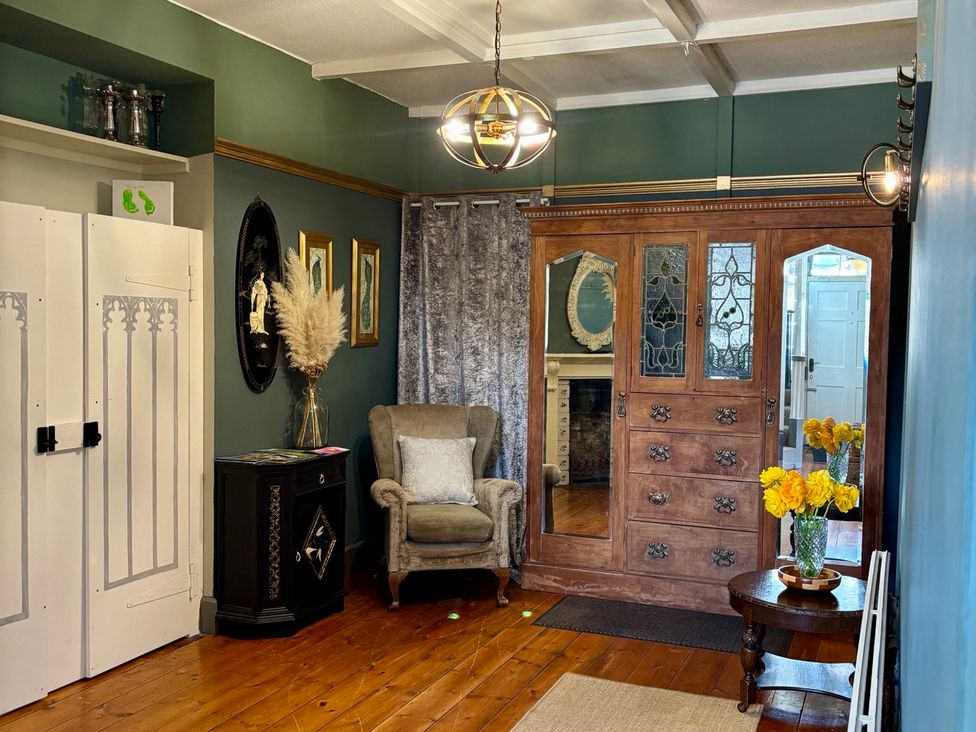 A hallway with an armchair, cabinet, and flowers at Humphreston House, Temple Cloud