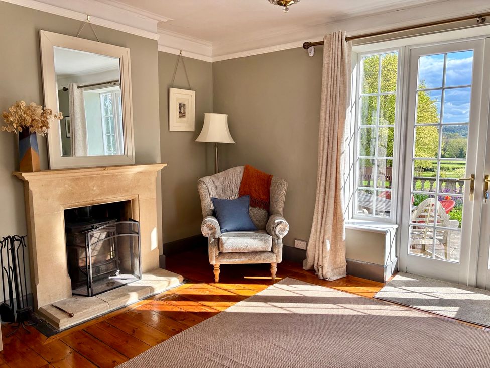 A living room with an armchair and fireplace at Humphreston House in Temple Cloud