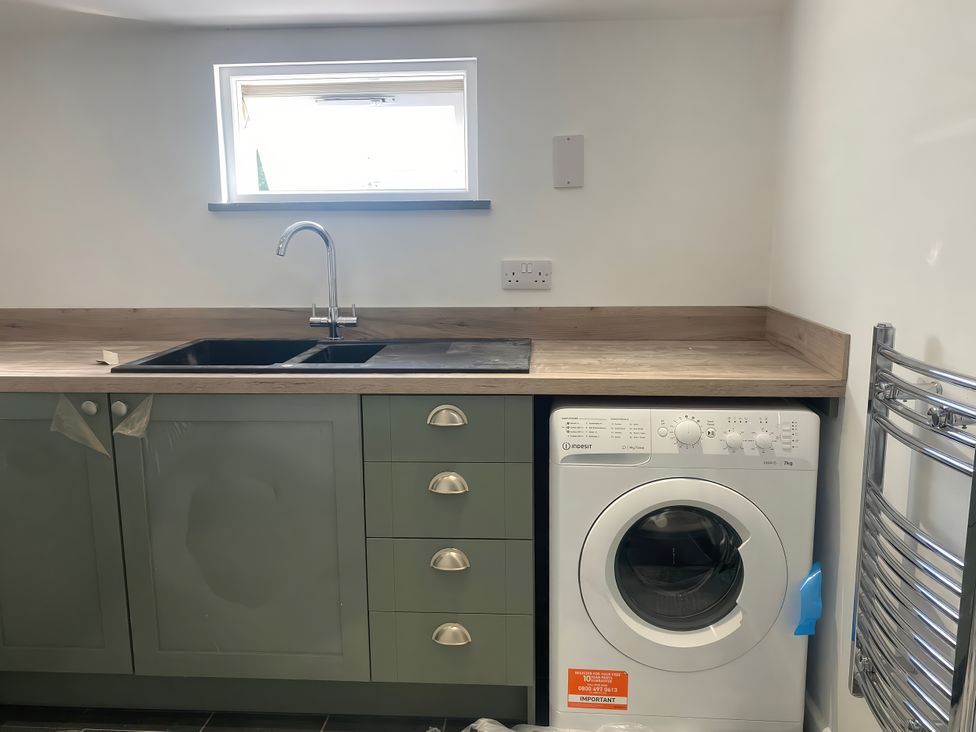 A kitchen with a sink and washing machine at Mys Hedra Farm in Penzance