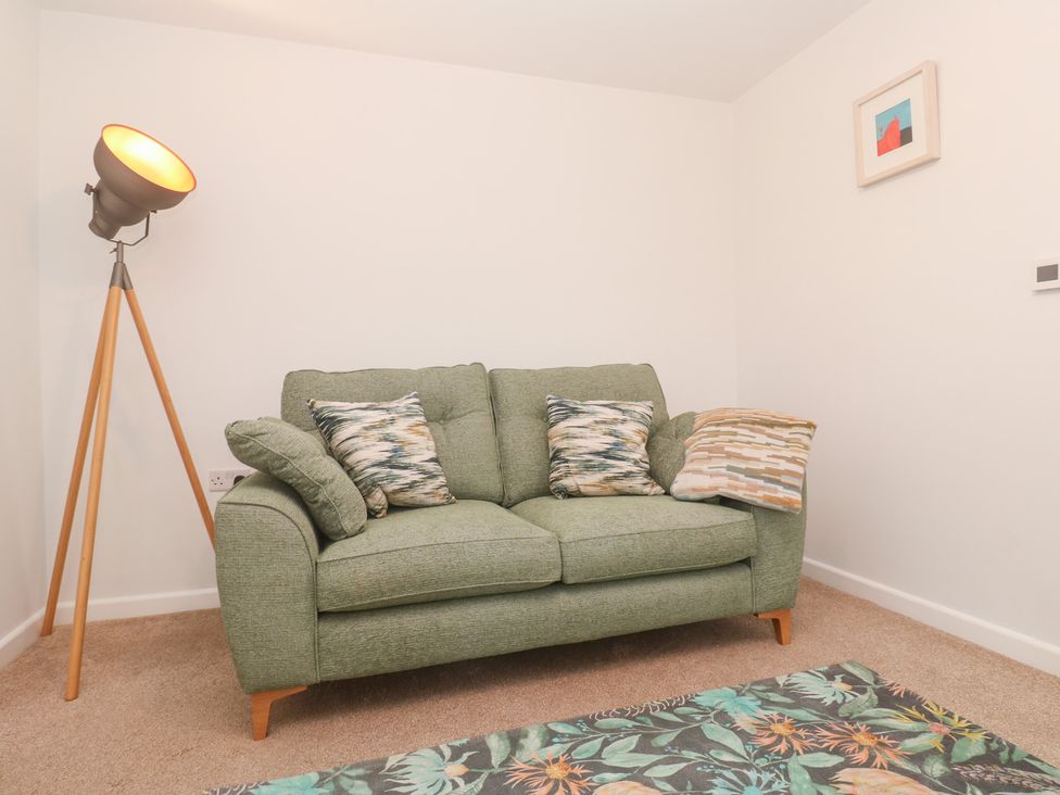 A living room with a sofa and floor lamp at Mys Hedra Farm St Buryan