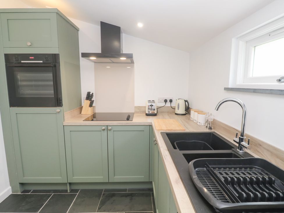 A kitchen with cabinets, oven, cooktop, sink and kettle at Mys Hedra Farm in St Buryan