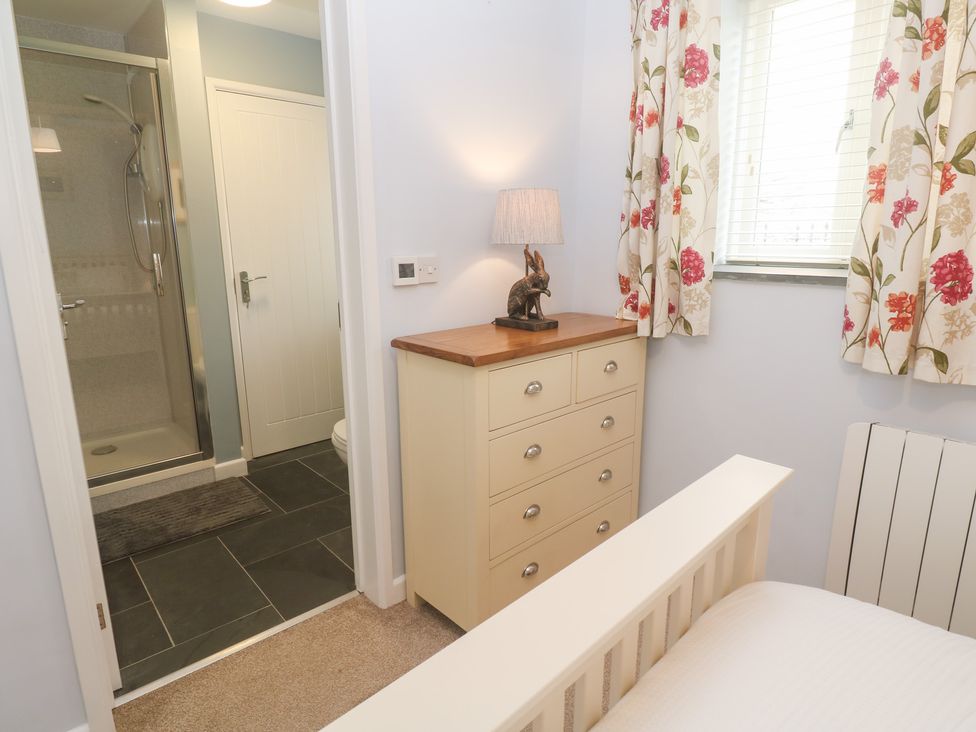 A bedroom with a dresser and a shower room door at Mys Hedra Farm in St Buryan