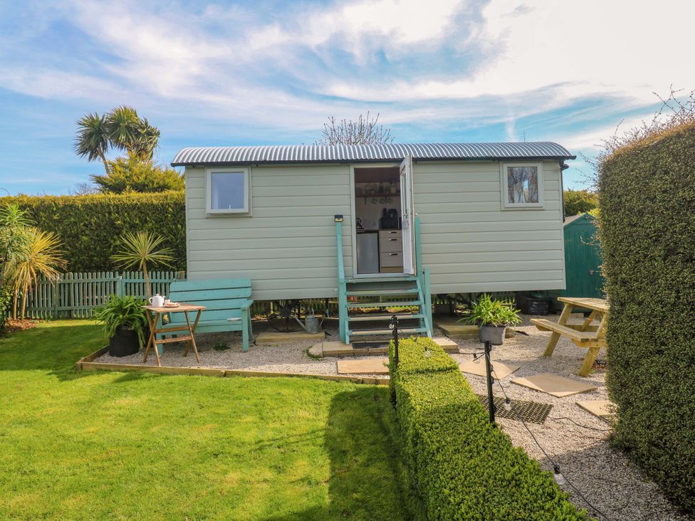 A shepherd hut with steps and furniture in a garden at Higher Merther Farm Shepherds Hut Helston