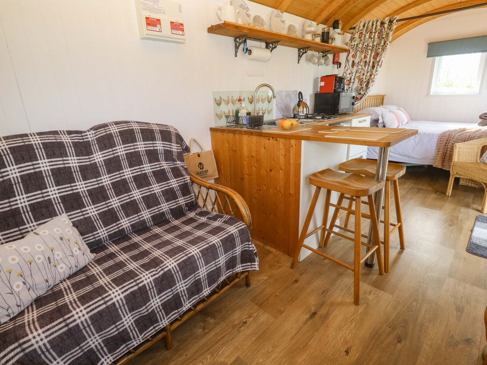 A hut interior with a sofa and kitchen area at Higher Merther Farm Shepherds Hut Helston