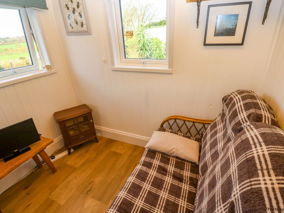 A snug area with a sofa and a television at Higher Merther Farm Shepherds Hut, Helston