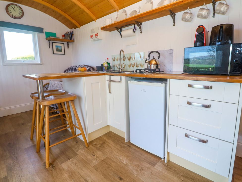 A kitchen with a gas stove and refrigerator at Higher Merther Farm Shepherds Hut in Helston
