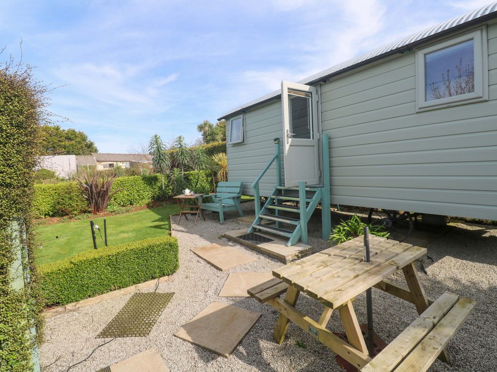 An outdoor area with a shepherd's hut, picnic table and chairs at Higher Merther Farm Shepherds Hut Helston