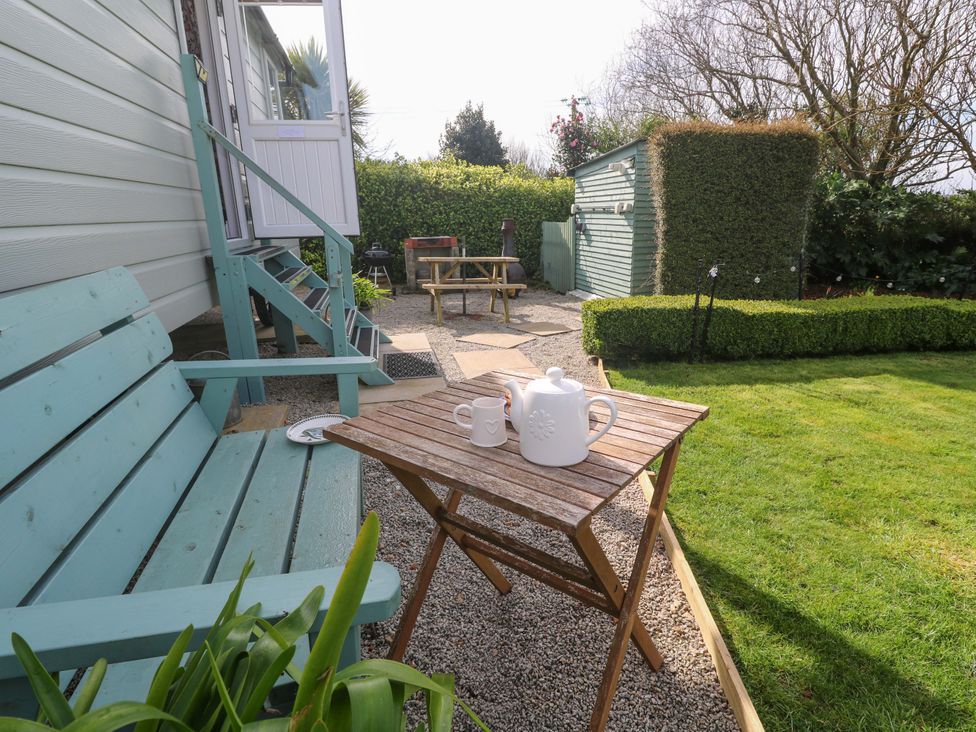 A garden with a table and teapot at Higher Merther Farm Shepherds Hut Helston
