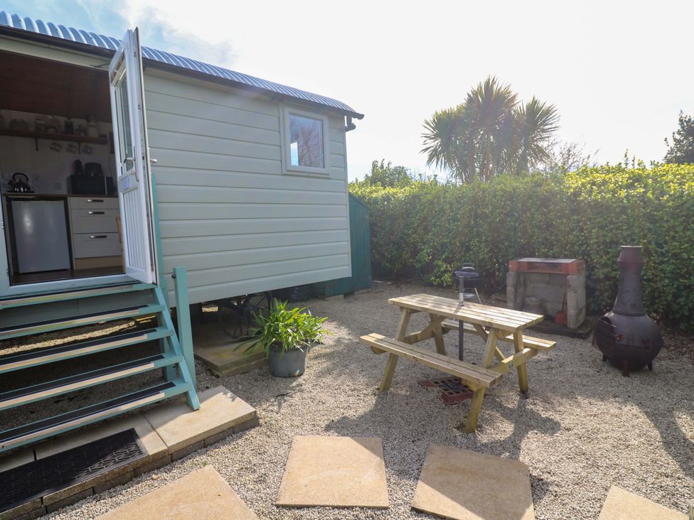 An outdoor area with a shepherd's hut and a picnic table at Higher Merther Farm Shepherds Hut Helston