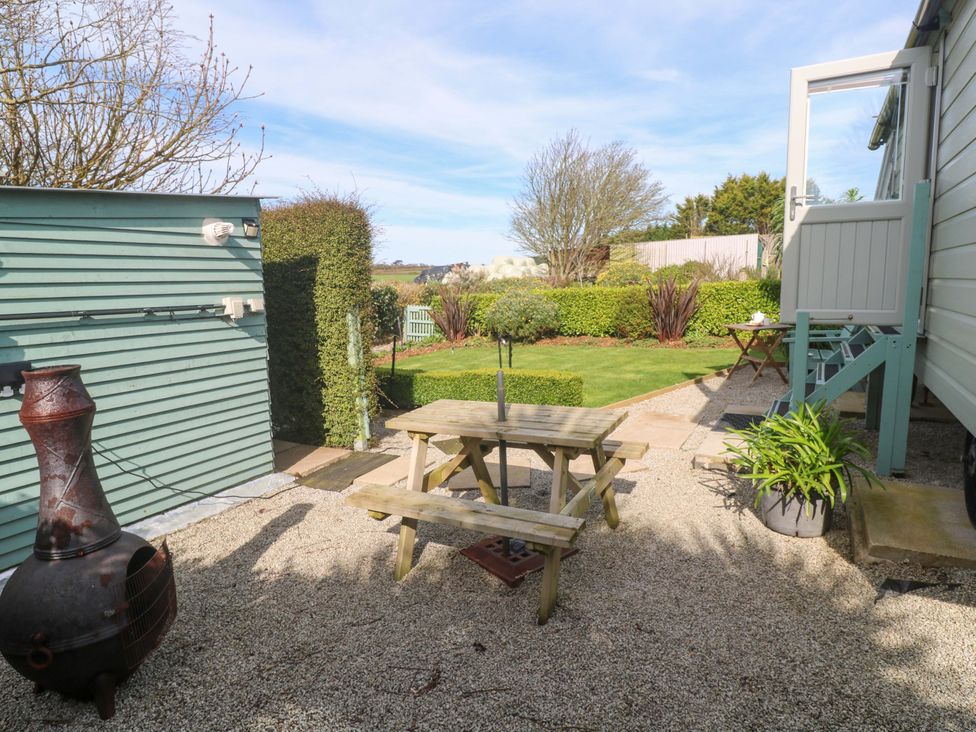A garden with a table and benches at Higher Merther Farm Shepherds Hut Helston