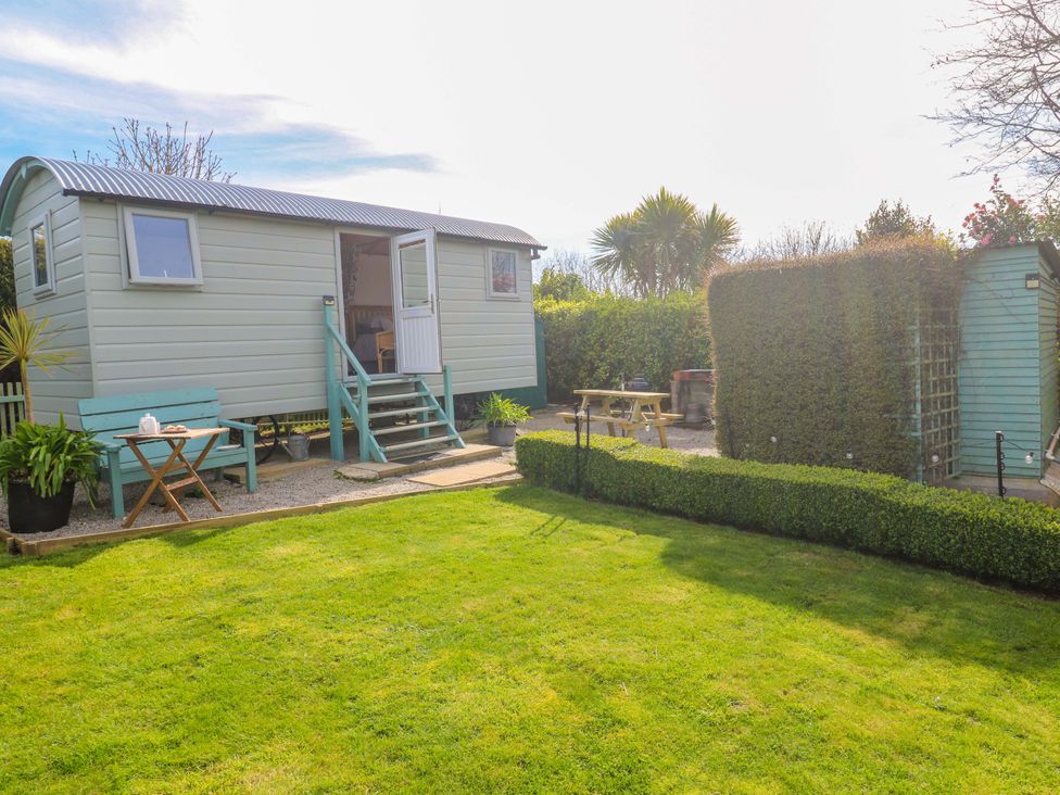 A garden with a shepherd's hut and seating at Higher Merther Farm Shepherds Hut in Helston