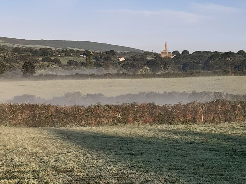 A landscape with a misty field and buildings in the background at Higher Merther Farm Shepherds Hut Sithney near Helston