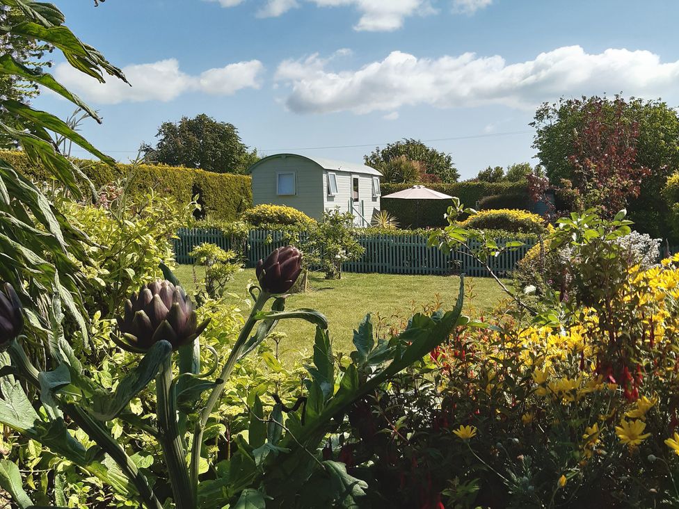 A garden with flowers and a caravan at Higher Merther Farm Shepherds Hut Sithney near Helston