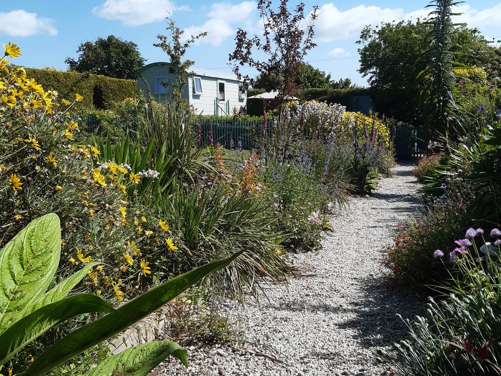 A garden with a gravel path and flowers at Higher Merther Farm Shepherds Hut in Sithney near Helston