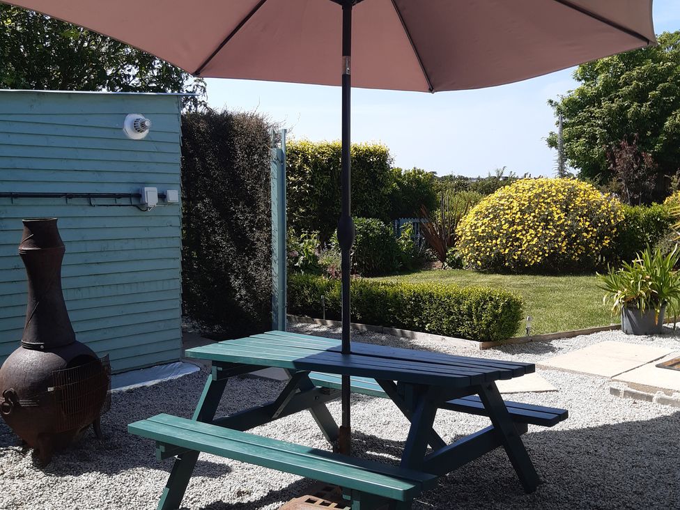 A garden with a table and umbrella at Higher Merther Farm Shepherds Hut in Sithney near Helston