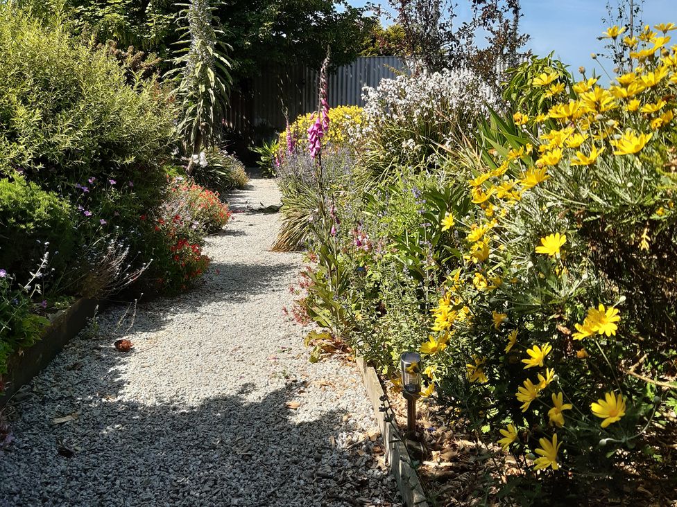 A garden pathway lined with flowers at Higher Merther Farm Shepherds Hut in Sithney near Helston