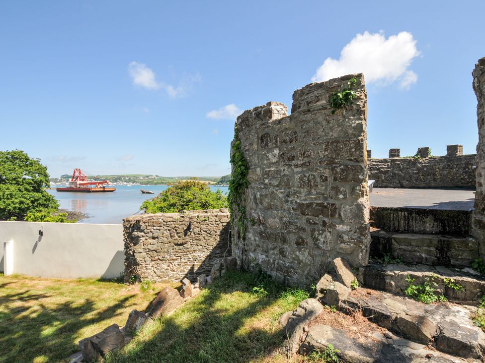 A view of a stone wall with greenery and a boat on the water at Boathyde in Northam