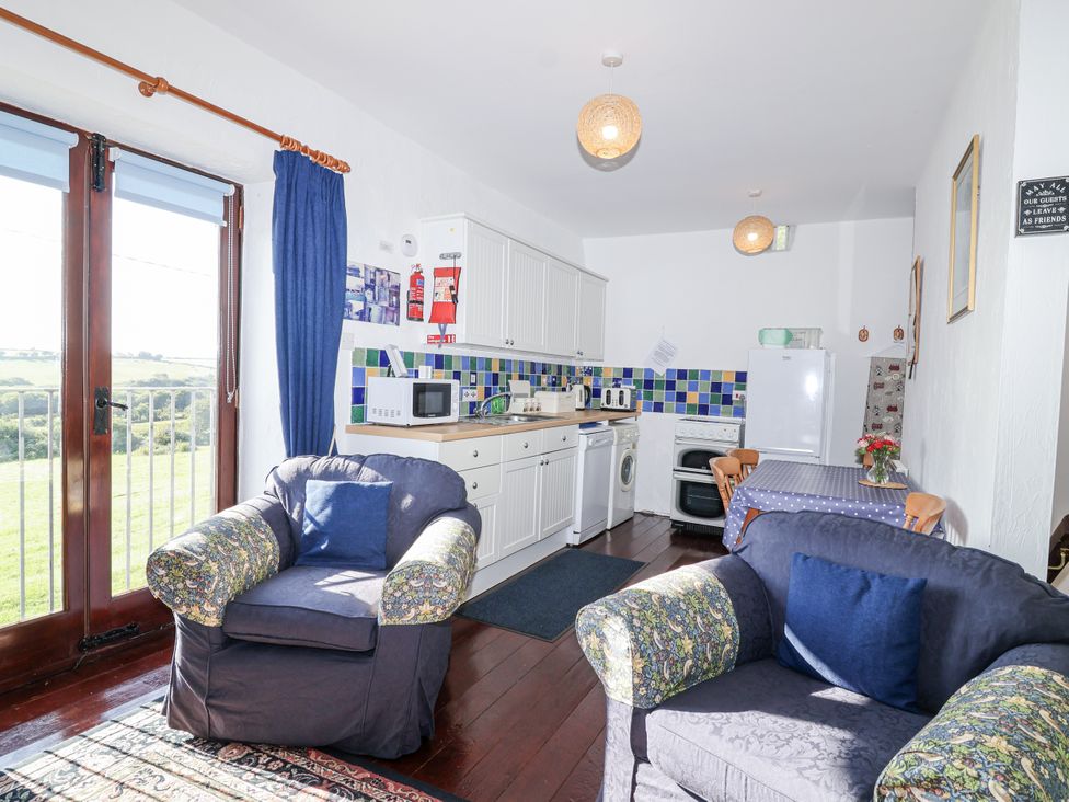 A kitchen with cabinets and a dining table at The Hayloft in Common Moor near Liskeard