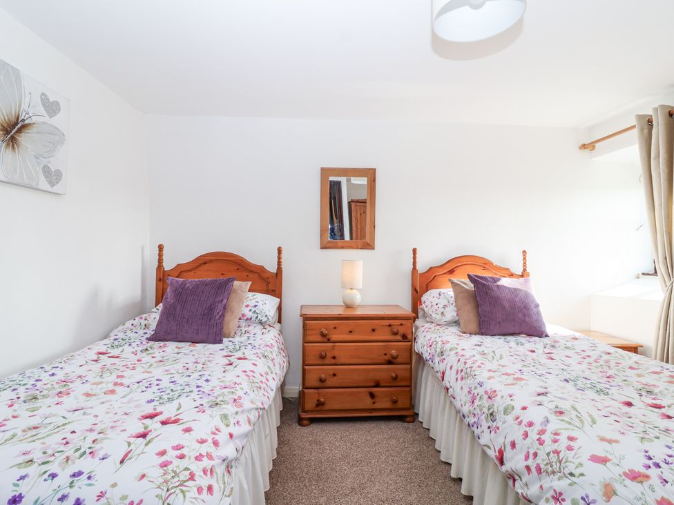 A bedroom with two single beds and a dresser at The Hayloft in Common Moor near Liskeard