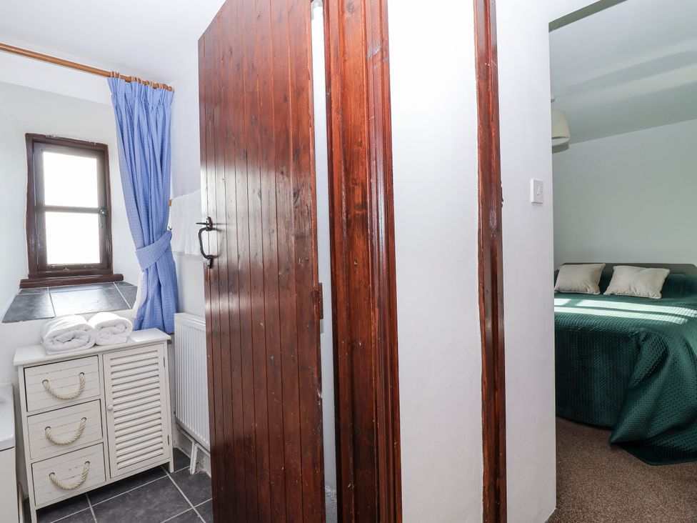 A bedroom with a bed and window leading to another room at The Hayloft Common Moor near Liskeard