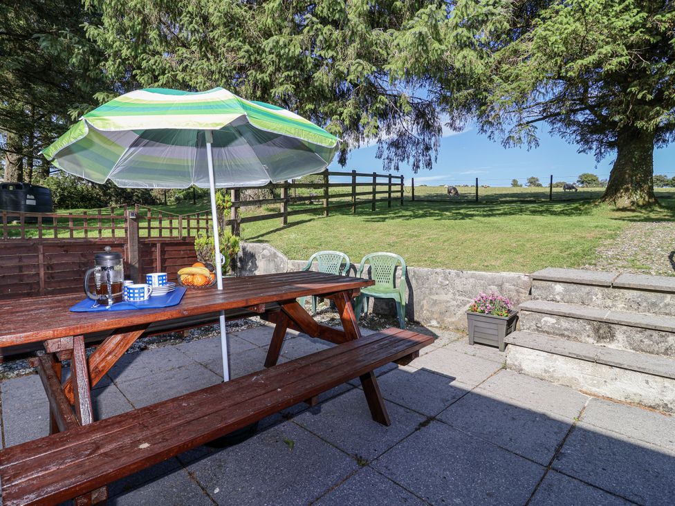 An outdoor patio with a table and chairs at The Hayloft in Common Moor near Liskeard