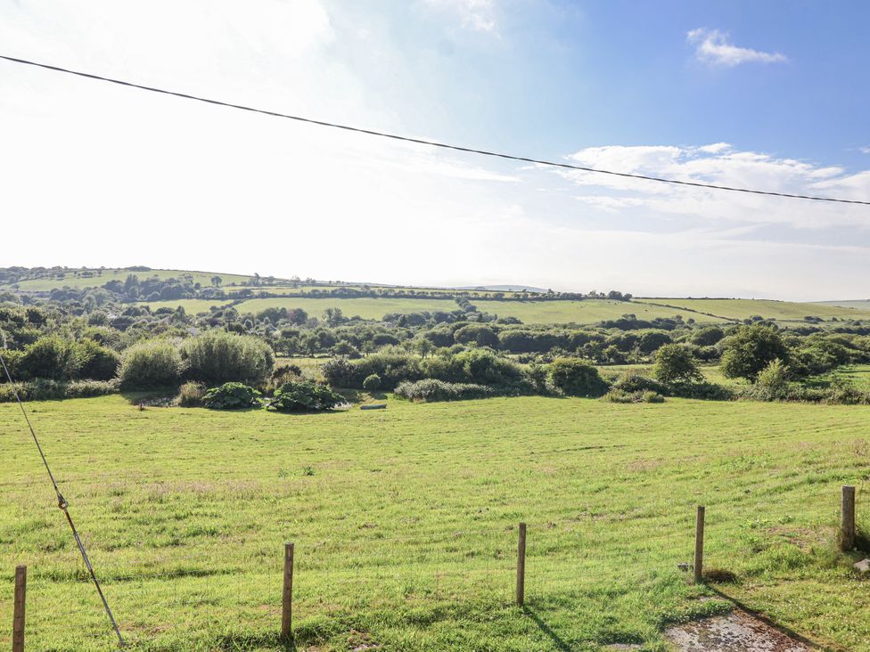 A view of a field with trees and hills at The Hayloft in Common Moor near Liskeard